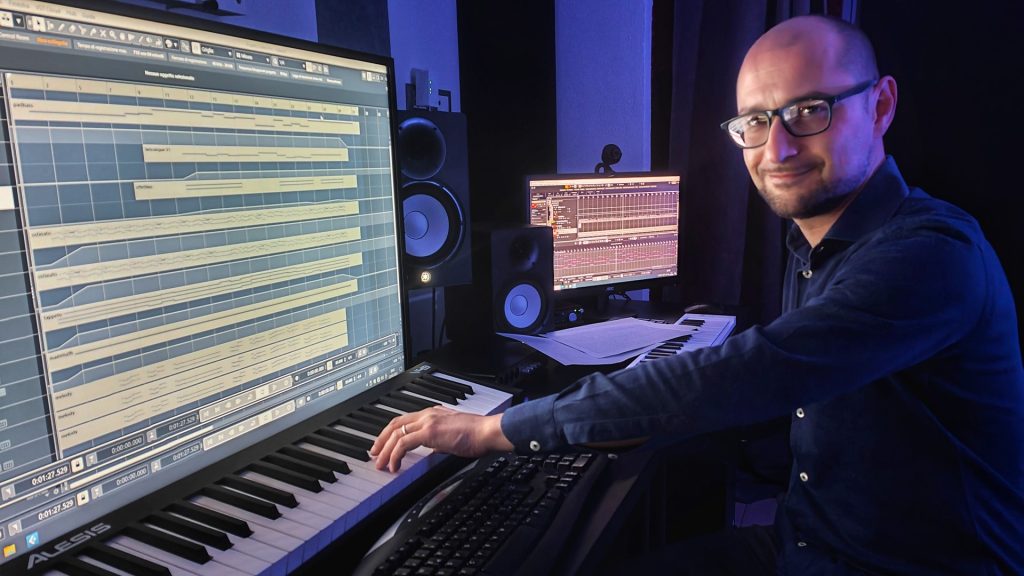 Uomo in studio di registrazione con pianoforte e computer